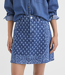 A person in a denim shirt models a blue denim mini skirt with a paisley pattern, against a plain white background. carousel Product Image 2