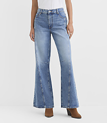 A person models light-wash flared jeans with brown boots against a plain white background. carousel Product Image 2