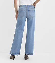 A person wearing light-wash wide-leg jeans with frayed hems stands against a plain white background. carousel Product Image 2