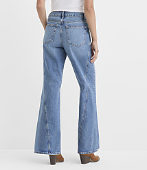 A person wearing light-wash flared jeans and brown heeled boots stands against a plain white background. carousel Product Image 2