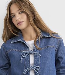 A young woman with long, light brown hair and a white t-shirt is wearing a blue denim jacket with two ties in the front, set against a plain white background. carousel Product Image 4