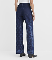 A person wearing dark wash wide-leg jeans with a blue floral pattern on the lower legs stands against a plain white background. carousel Product Image 2
