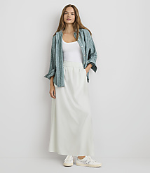 A woman in a white tank top, a green patterned shirt, and a long white skirt stands against a plain white background. carousel Product Image 1