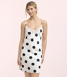 A woman in a white polka dot slip dress with lace trim stands against a soft pink background. carousel Product Image 1