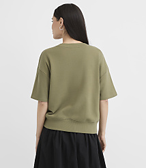 A woman in a green sweatshirt and black skirt stands against a plain white background. carousel Product Image 3