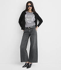 A woman in a black cardigan, grey graphic t-shirt, and wide-leg jeans stands against a plain white background. carousel Product Image 3