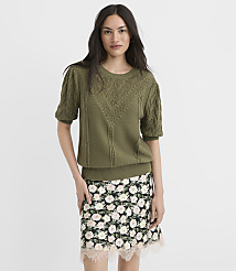 A woman in a green sweater and floral skirt stands against a plain white background. carousel Product Image 2