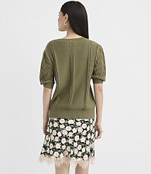 A woman in a green sweater and floral skirt stands against a plain white background. carousel Product Image 3