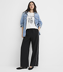 A woman in a graphic tee, denim jacket, and wide-leg pants stands against a plain white background. carousel Product Image 2