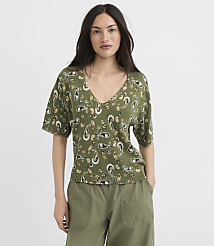 A woman in a green paisley t-shirt and olive pants stands against a plain white background. carousel Product Image 2