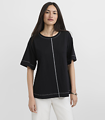 A woman in a black t-shirt with white stitching stands against a plain white background. carousel Product Image 1