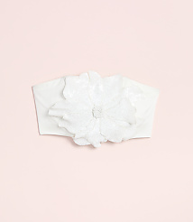 A white fabric headband with a large, ornate flower adorns a soft pink background. carousel Product Image 4