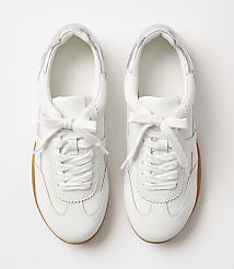 A pair of white leather sneakers with silver accents and gum soles rests on a plain white background. carousel Product Image 3