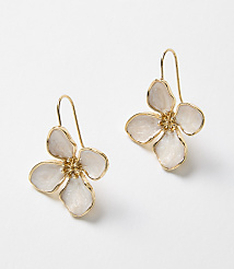 A pair of delicate gold flower-shaped earrings with white enamel petals rest against a plain white background. carousel Product Image 1