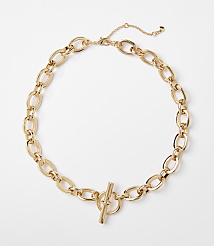A gold chain necklace with a toggle clasp lies on a plain white background. carousel Product Image 1