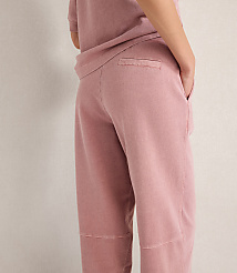 A person in a pink t-shirt and pants stands against a textured white wall. carousel Product Image 3