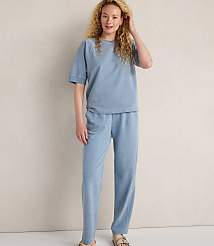 A woman in a light blue loungewear set stands against a textured, light-colored wall. carousel Product Image 2