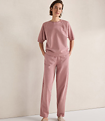 A woman in a pink loungewear set stands against a plain, textured background. carousel Product Image 2