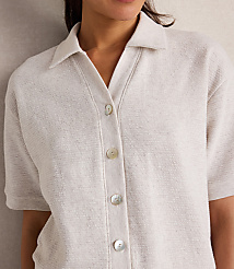 A woman in a textured cream collared shirt with pearl buttons is shown against a neutral, textured background. carousel Product Image 3