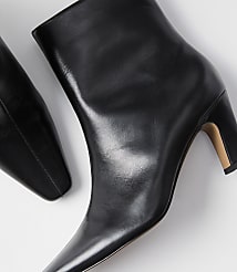 A pair of sleek black leather ankle boots with pointed toes and block heels rests on a plain white background. carousel Product Image 2