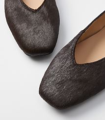 Two dark brown, furry flats with square toes are in the foreground against a plain white background. carousel Product Image 2