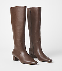 A pair of brown leather knee-high boots with block heels stand on a white surface against a plain white background. carousel Product Image 1