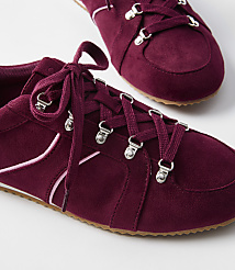Burgundy suede sneakers with pink accents and silver eyelets are in the foreground, with another shoe blurred in the background. carousel Product Image 2
