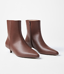 A pair of brown leather ankle boots with pointed toes and kitten heels are displayed against a plain white background. carousel Product Image 1