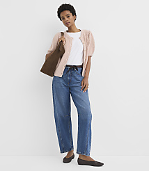 A woman in a pink cardigan and jeans stands against a plain white background, carrying a brown bag. carousel Product Image 2