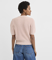 A woman in a pink ribbed sweater and blue jeans stands against a plain white background. carousel Product Image 3