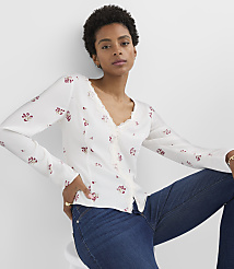 A woman in a floral blouse and jeans poses against a plain white background. carousel Product Image 1