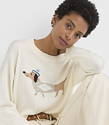A woman in a cream sweater with a dachshund design smiles against a plain background. carousel Product Image 1