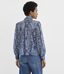 A woman in a blue paisley blouse and jeans stands against a plain white background. carousel Product Image 4