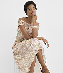 A woman in a patterned off-the-shoulder dress sits against a plain white background. carousel Product Image 2