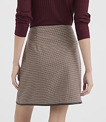 A woman in a burgundy sweater models a brown and tan patterned mini-skirt against a plain white background. carousel Product Image 3