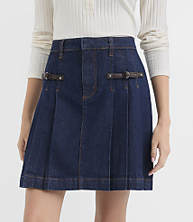 A dark denim pleated skirt with leather buckle details is worn by a person against a plain white background. carousel Product Image 2