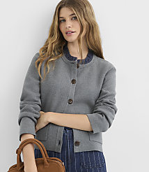 A young woman with long, wavy blonde hair stands in the foreground wearing a grey cardigan and blue striped pants, with a brown handbag at her side, against a plain white background. carousel Product Image 1