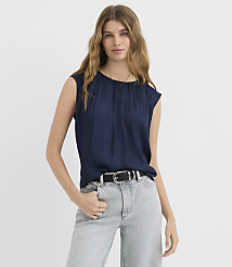 A woman in a navy blue top and light gray jeans stands against a plain white background. carousel Product Image 1