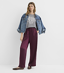 A woman in a denim jacket and burgundy satin pants stands against a plain white background. carousel Product Image 2