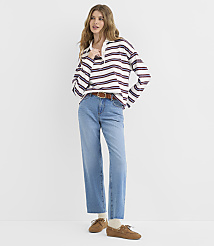 A woman in a striped shirt and jeans stands against a plain white background. carousel Product Image 1