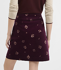 A person wearing a burgundy A-line skirt with a floral pattern stands against a plain white background. carousel Product Image 3