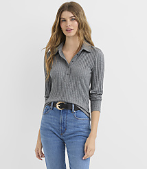 A woman in a grey ribbed polo shirt and blue jeans stands against a plain white background. carousel Product Image 1