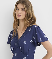 A woman with wavy blonde hair and a floral blue dress is shown against a plain white background. carousel Product Image 1
