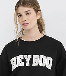 A young woman with blonde hair pulled back in a ponytail wears a black sweatshirt with "BEYBOO" printed in white letters, against a plain white background. carousel Product Image 4
