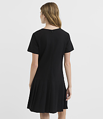 A woman in a black dress with a pleated skirt stands against a plain white background. carousel Product Image 3