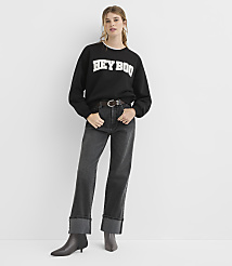 A woman in a black sweatshirt and cuffed jeans stands against a plain white background. carousel Product Image 2