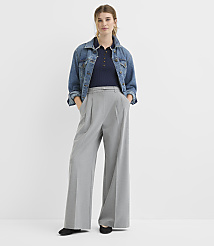 A woman in a denim jacket, navy polo shirt, and wide-leg gray pants stands against a plain white background. carousel Product Image 1