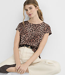 A young woman with a leopard print t-shirt and light-colored pants sits against a plain white background. carousel Product Image 1