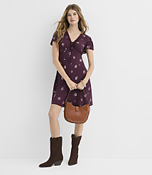 A woman in a floral dress and cowboy boots stands against a plain white background, holding a brown studded purse. carousel Product Image 2