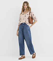 A woman in a floral sweater and wide-leg jeans stands against a plain white background. carousel Product Image 2